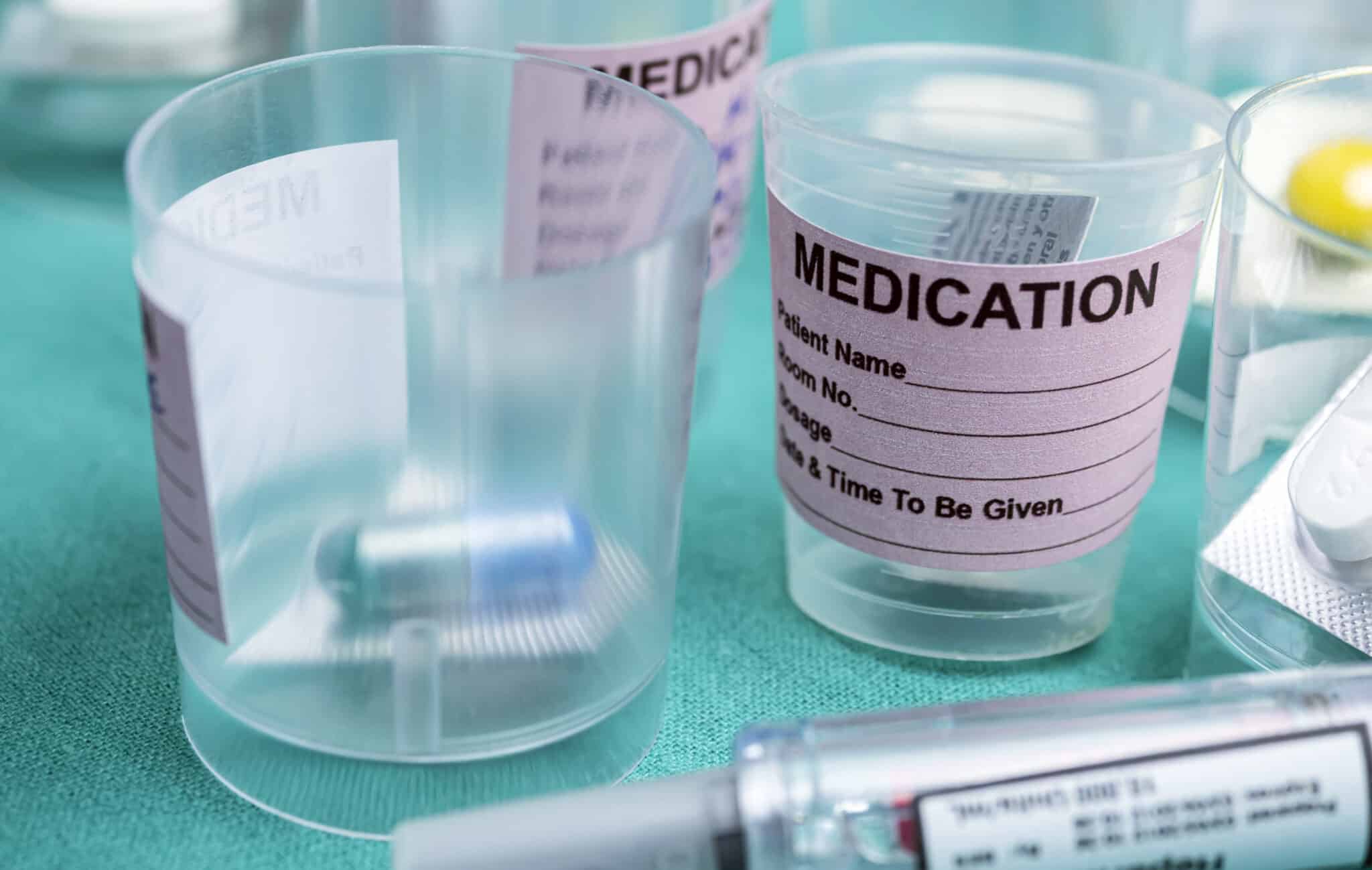 Diverse medication in glasses monodose along with insulin injectors in hospital, conceptual image