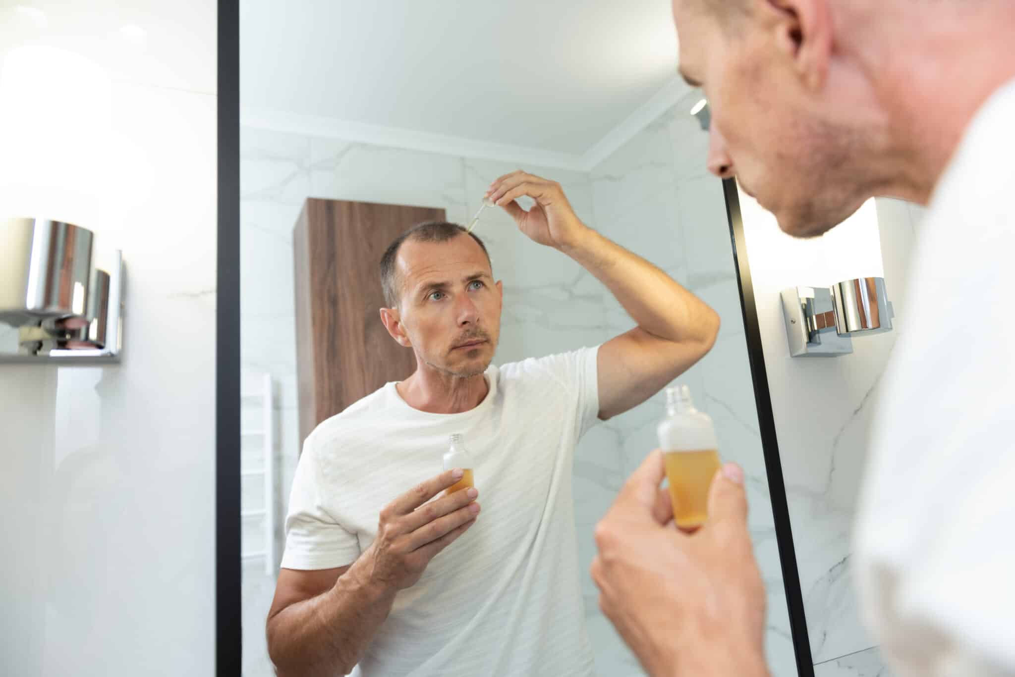 Man applying dropper vitamin on head. Baldness treatment concept