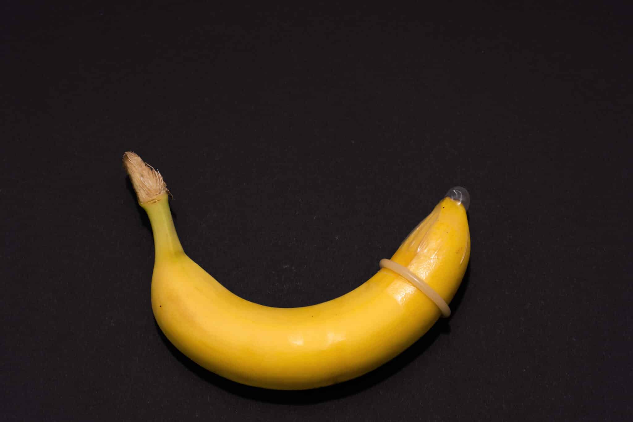 Banana with Condom on black background. Sexual Health and Educat